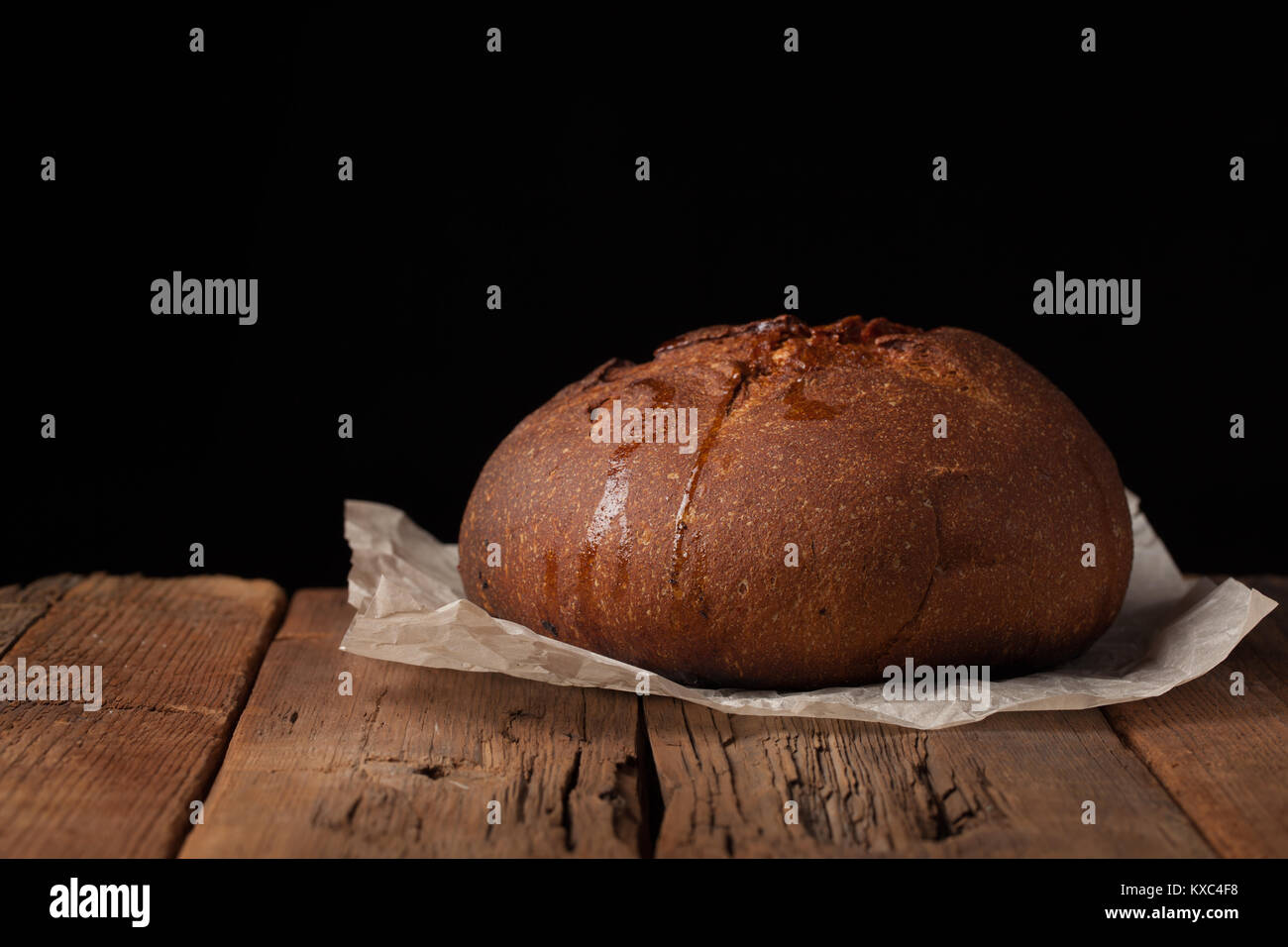 Tasty rustic bread on wooden table on black background with copy space ...