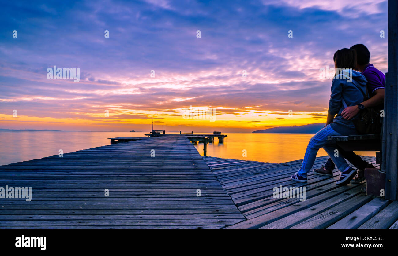 The romantic young couple is hugging on a wooden pier that stretched ...