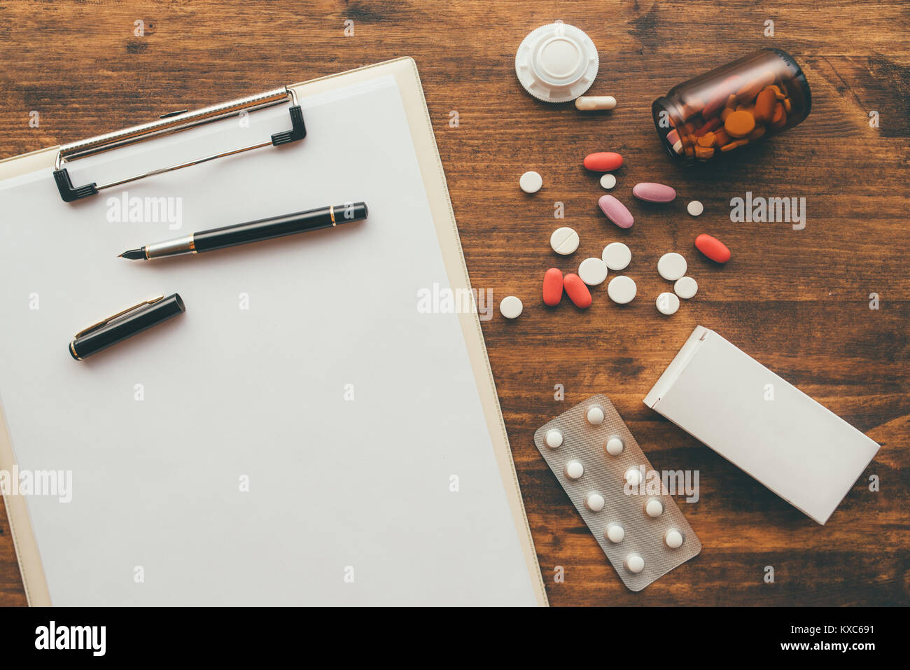 Overhead view of medical doctor office desk with note pad clipboard and prescription drugs Stock Photo