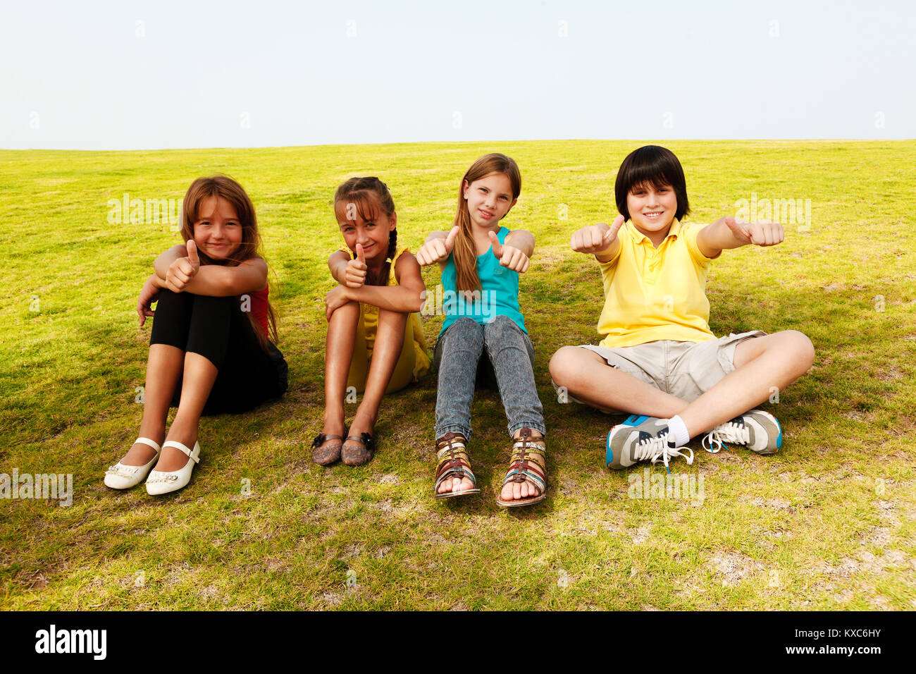 Group of four happy children showing thumbs up outdoors Stock Photo - Alamy
