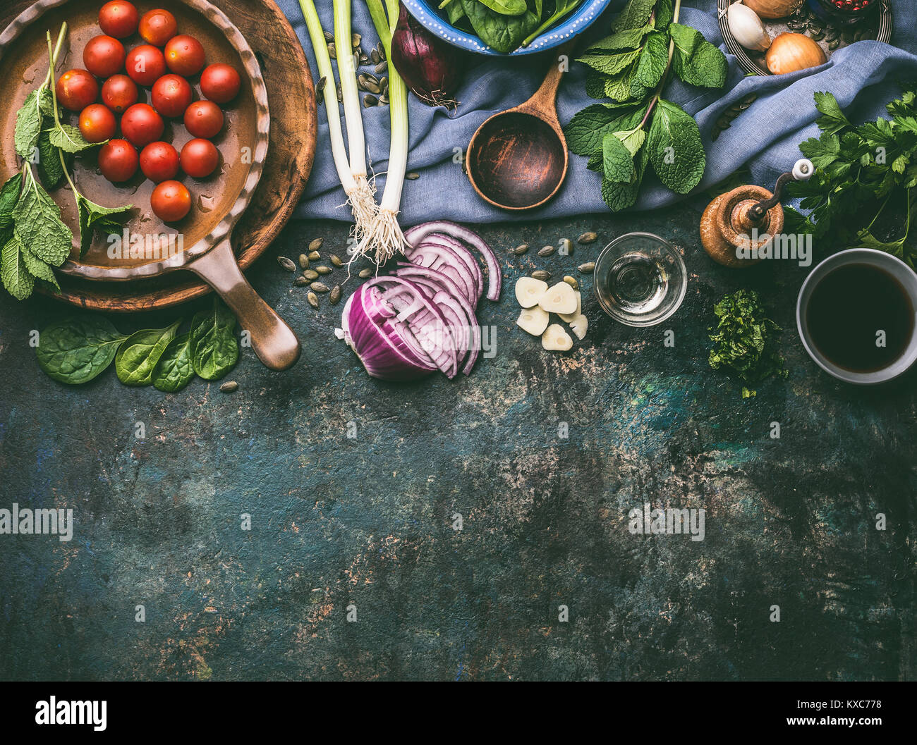 Vegetarian cooking ingredients with fresh seasoning on rustic kitchen table with spoon , top view, place for text.  Clean, vegan food and healthy eati Stock Photo