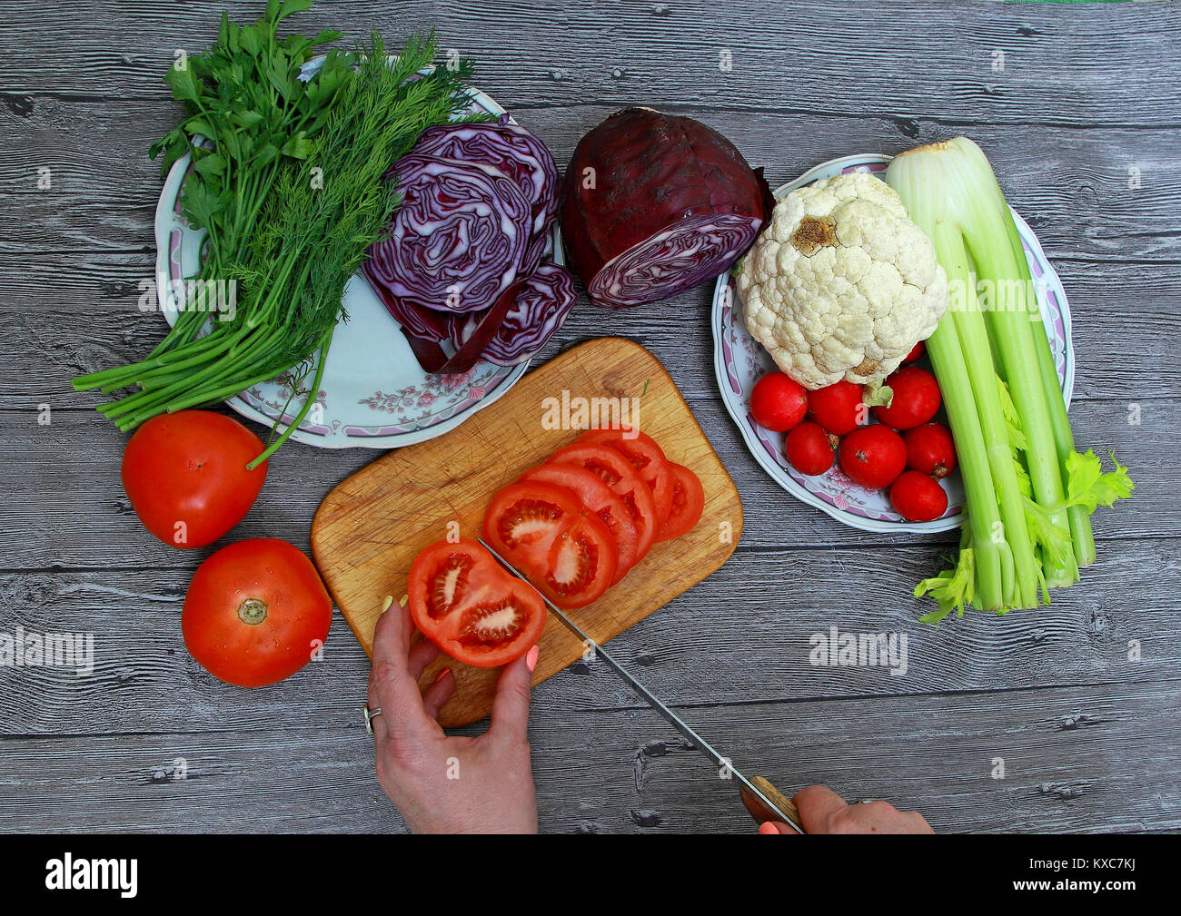 Women's hands cut tomato for salad with vegetables Stock Photo Alamy