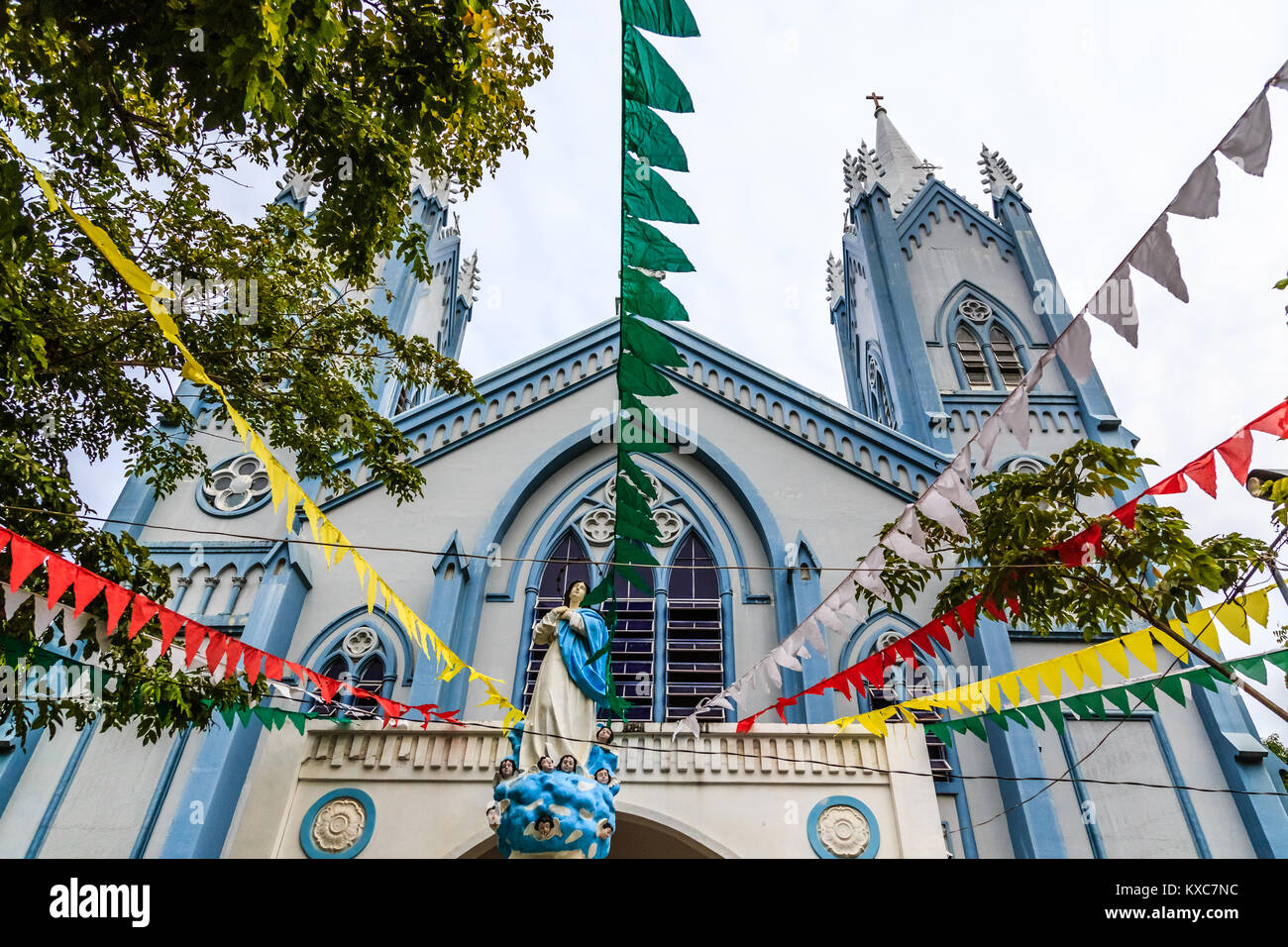 Blue Catholic church decorated with flags and Saint Mary statue with angels , Puerto Princessa, Palawan. Philippines Stock Photo