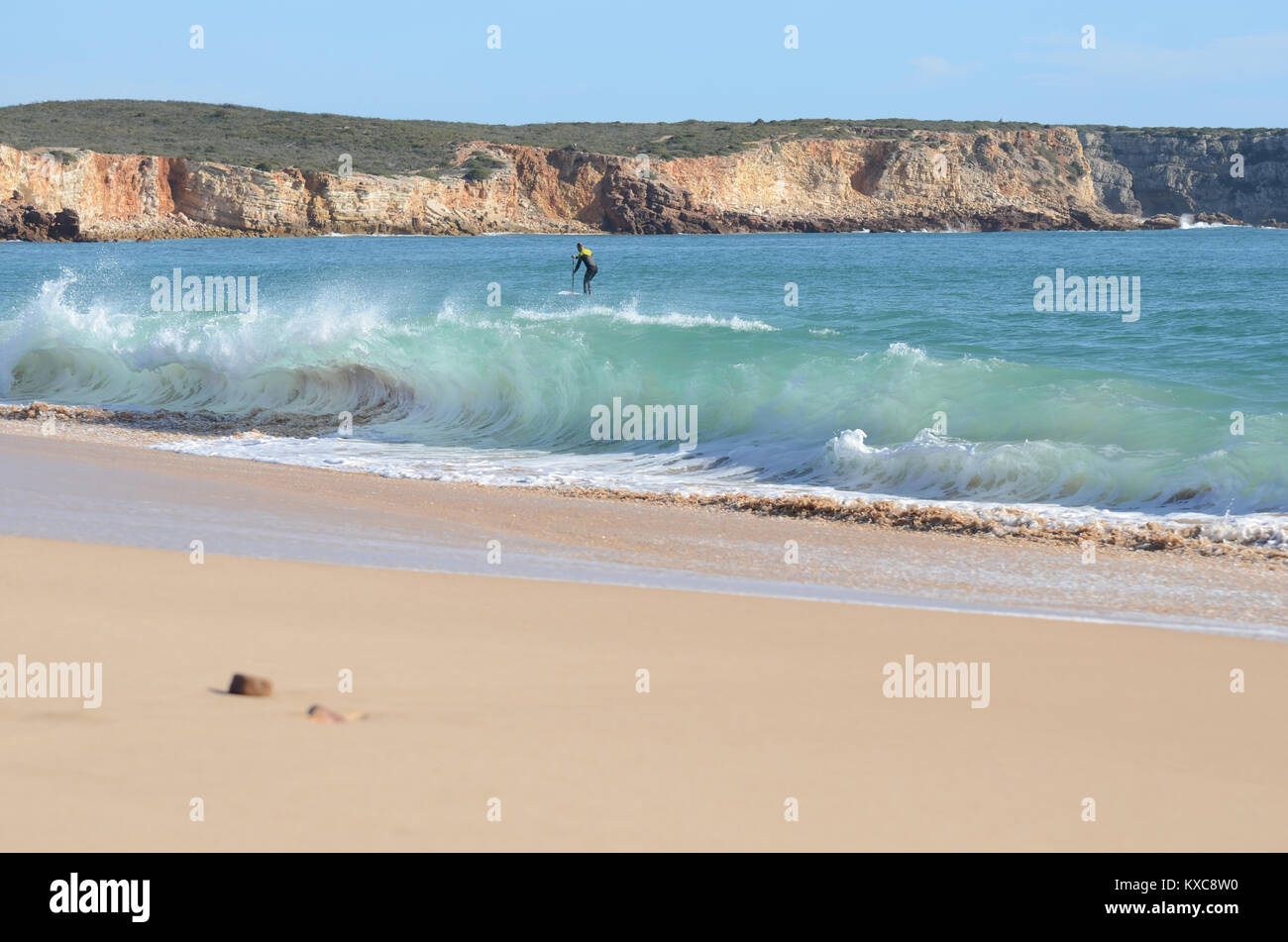 Beach with paddle boarder surfing waves Stock Photo