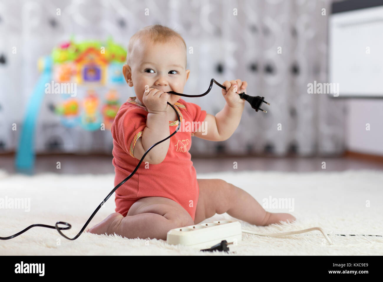 8 months age baby curious looking with electronic plug Stock Photo - Alamy