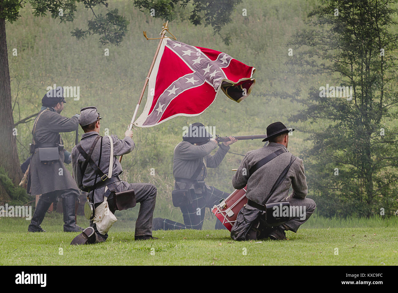 A group of four confederate soldiers firing weapon with a southern flag at a reenactment Stock Photo
