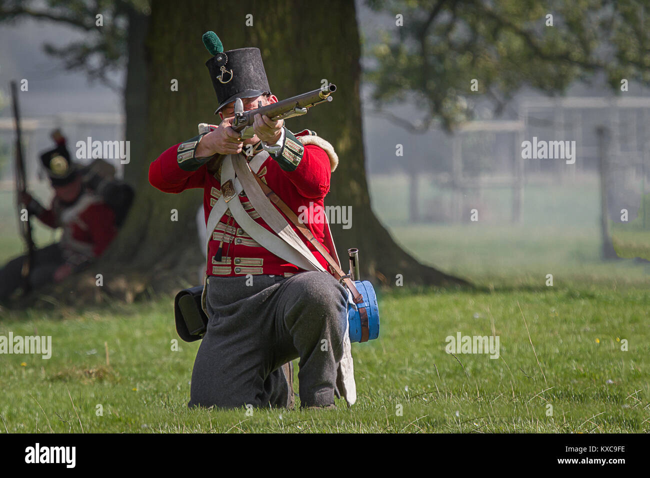 An english red coat kneeling down aiming his musket preparing to fire at a reenactment Stock Photo