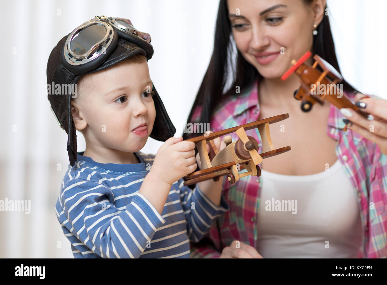 Mother and child son are playing with wooden planes indoors. Stock Photo