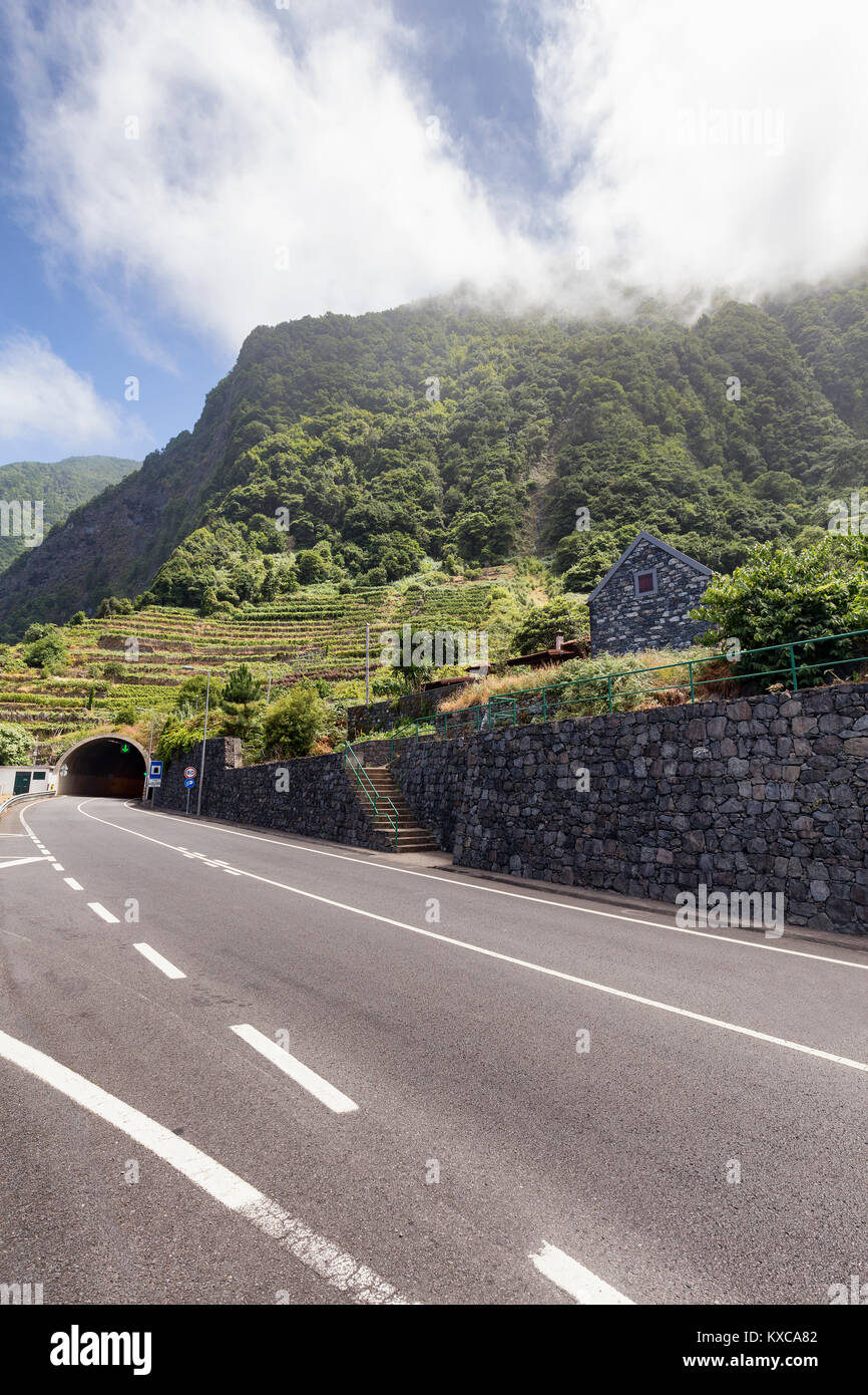 Clouds gather above terraced vinyards and a traditional brick building near Seixal in Madeira. Stock Photo