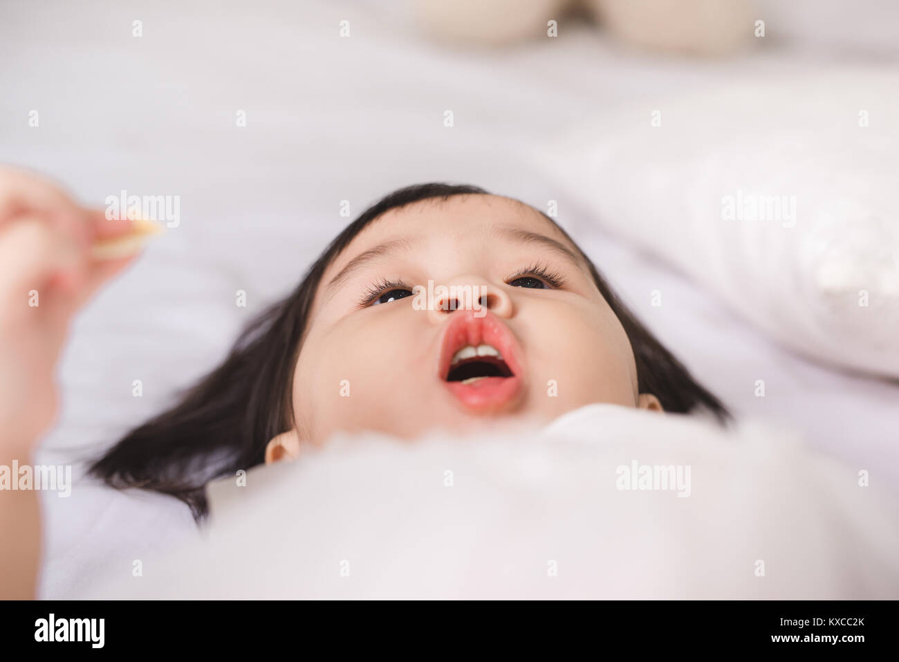 Cute little girl eating cookie at home Stock Photo