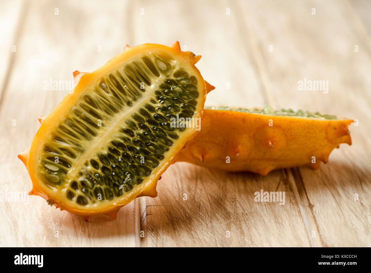 closeup of a kiwano or horned melon cut in halves on a white rustic