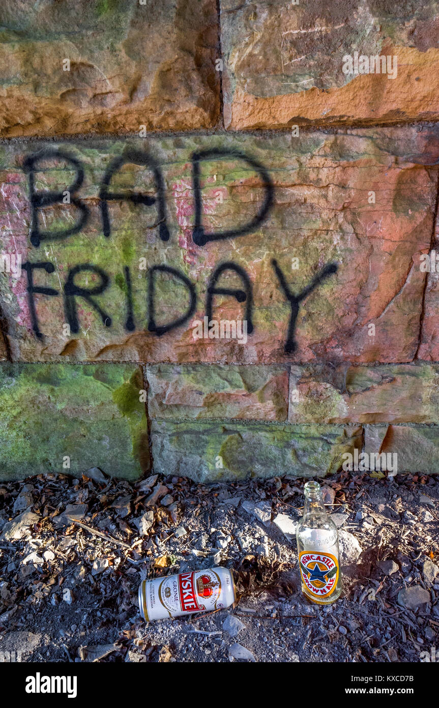 Empty and discarded beer bottle and can against a stone wall with Bad Friday sprayed onto it. Stock Photo