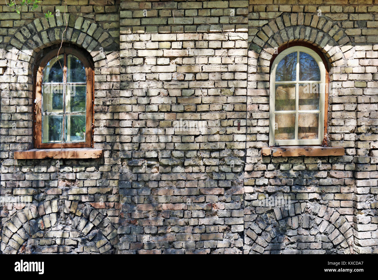 Two blind windows in the yellow ruined brick wall of the old aged no name castle. Panoramic collage from several outdoor sunny  spring day  shots Stock Photo