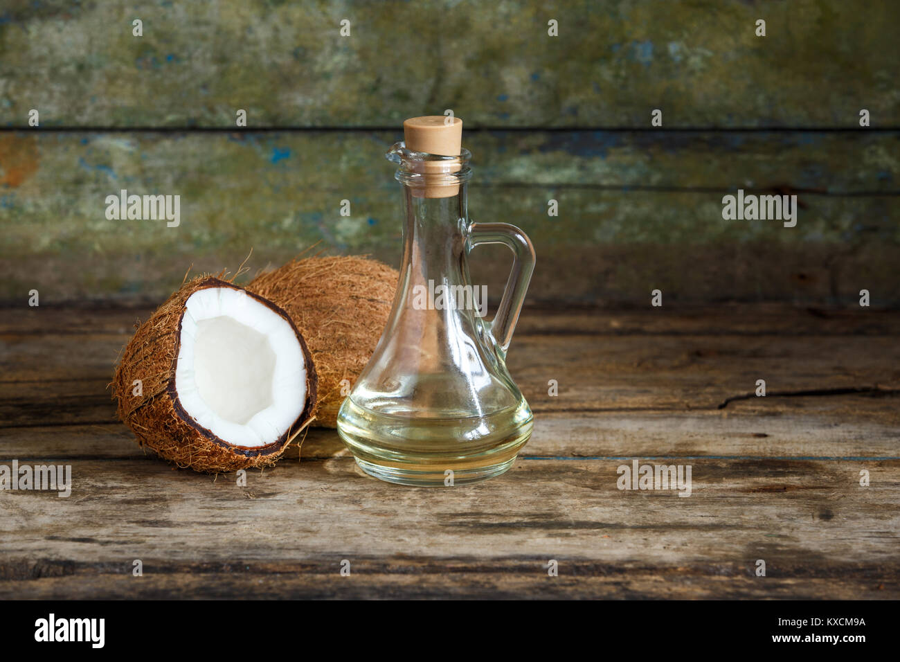 Fresh whole and cut in half coconuts with coconut oil on wooden
