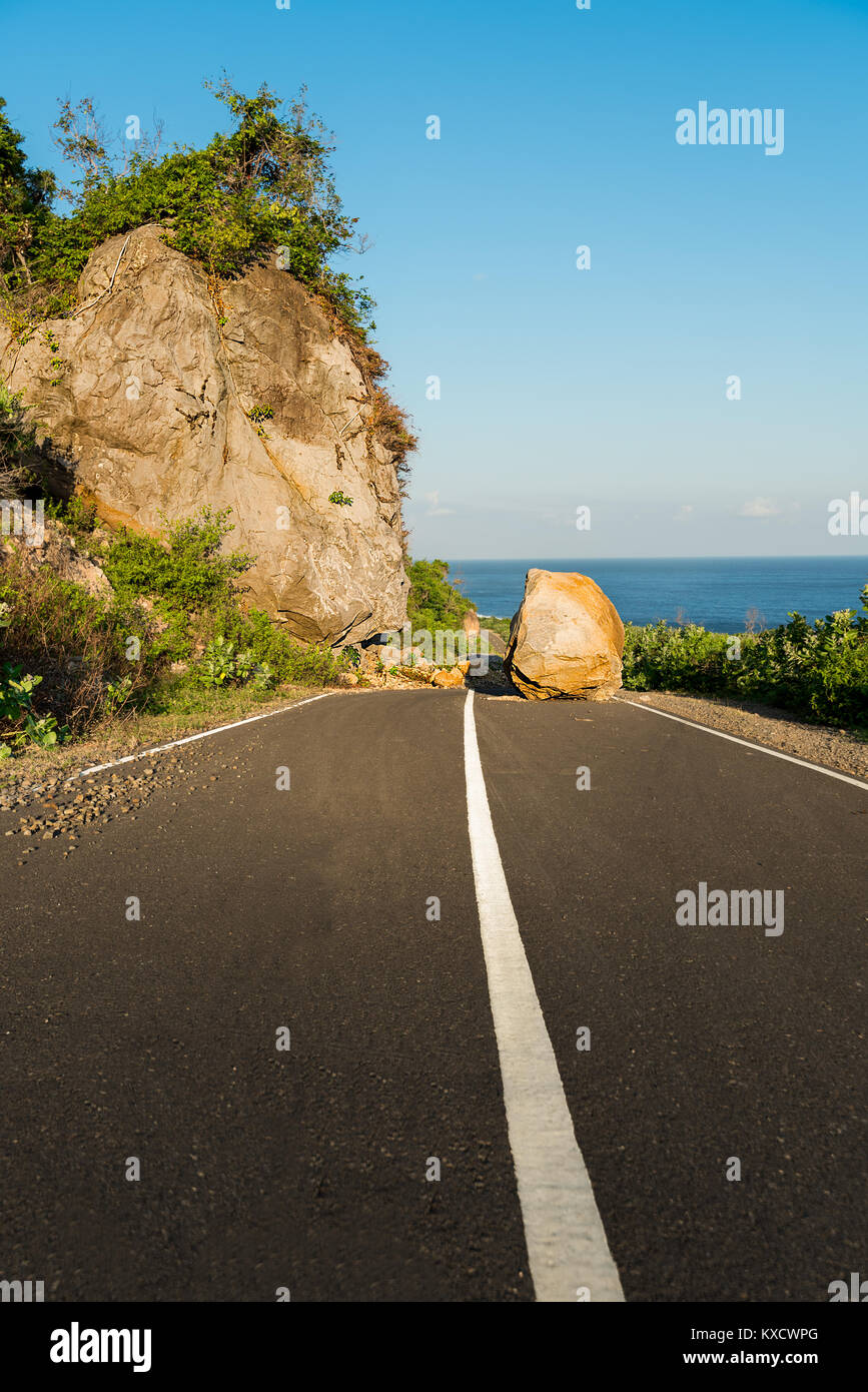 New asphalt coastal road path route blocked by land slide / rock fall / large boulder. Stock Photo