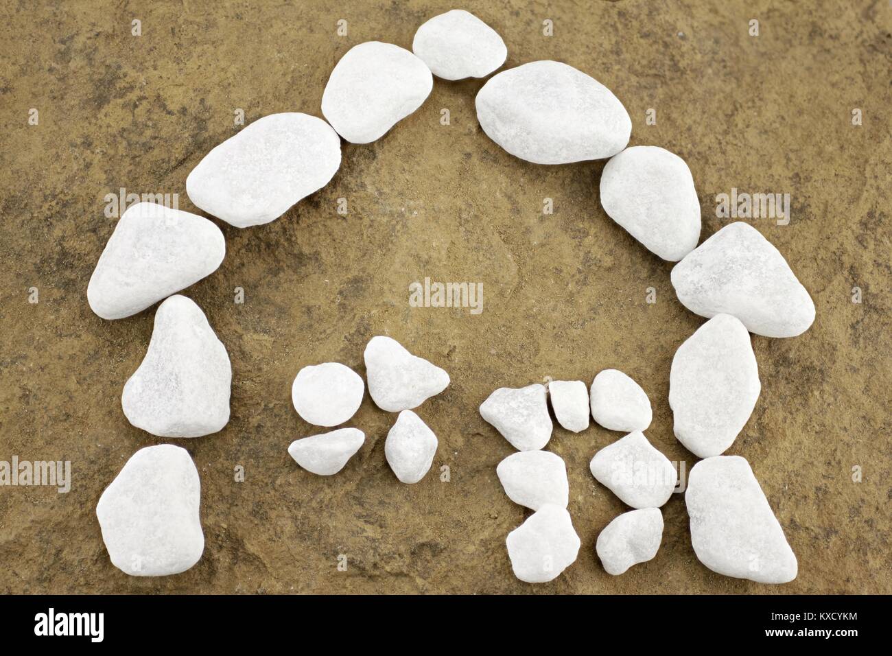 little house made of white pebbles in front of brown stone Stock Photo
