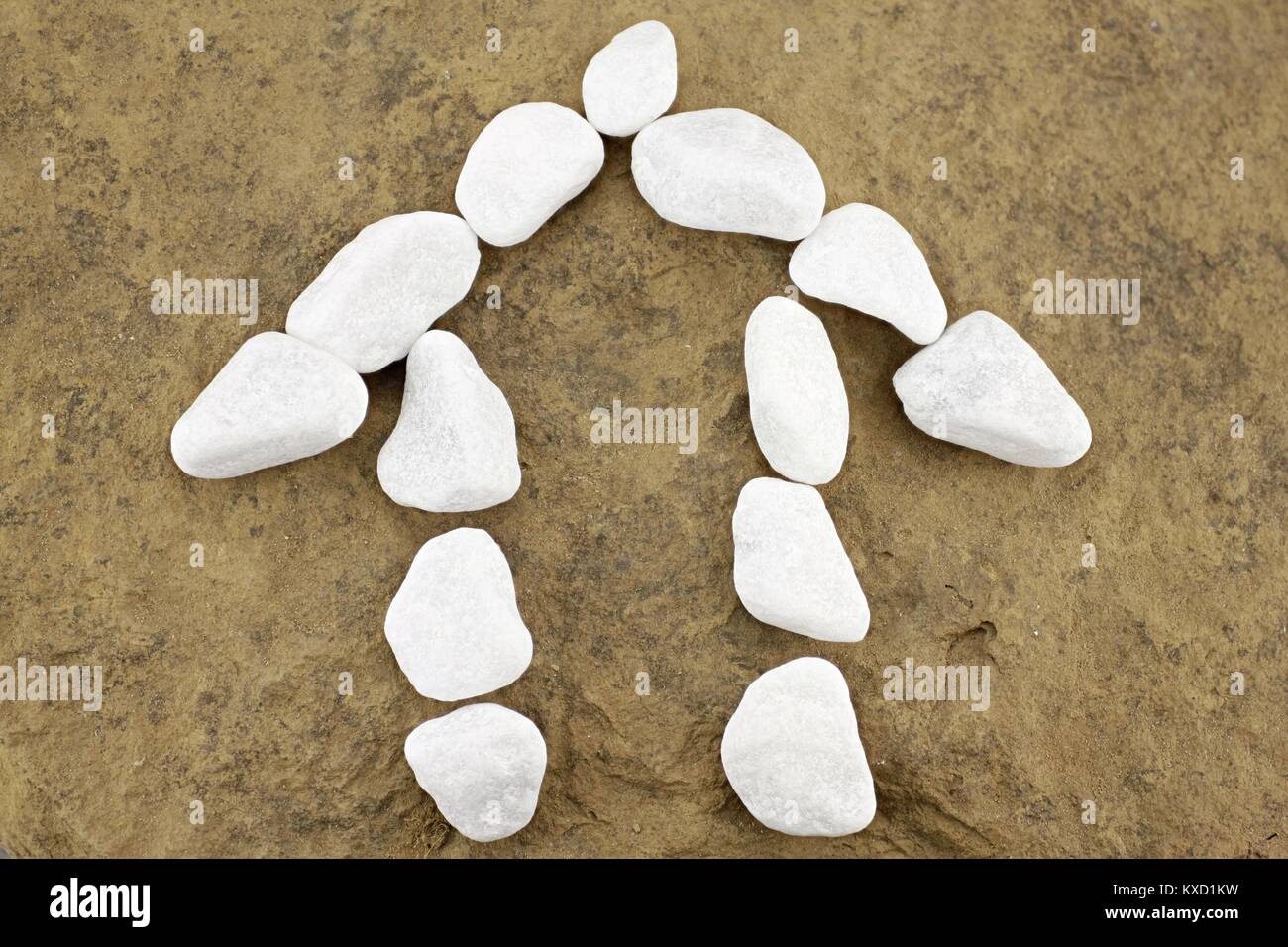 Small house of white pebbles in front of brown stone Stock Photo