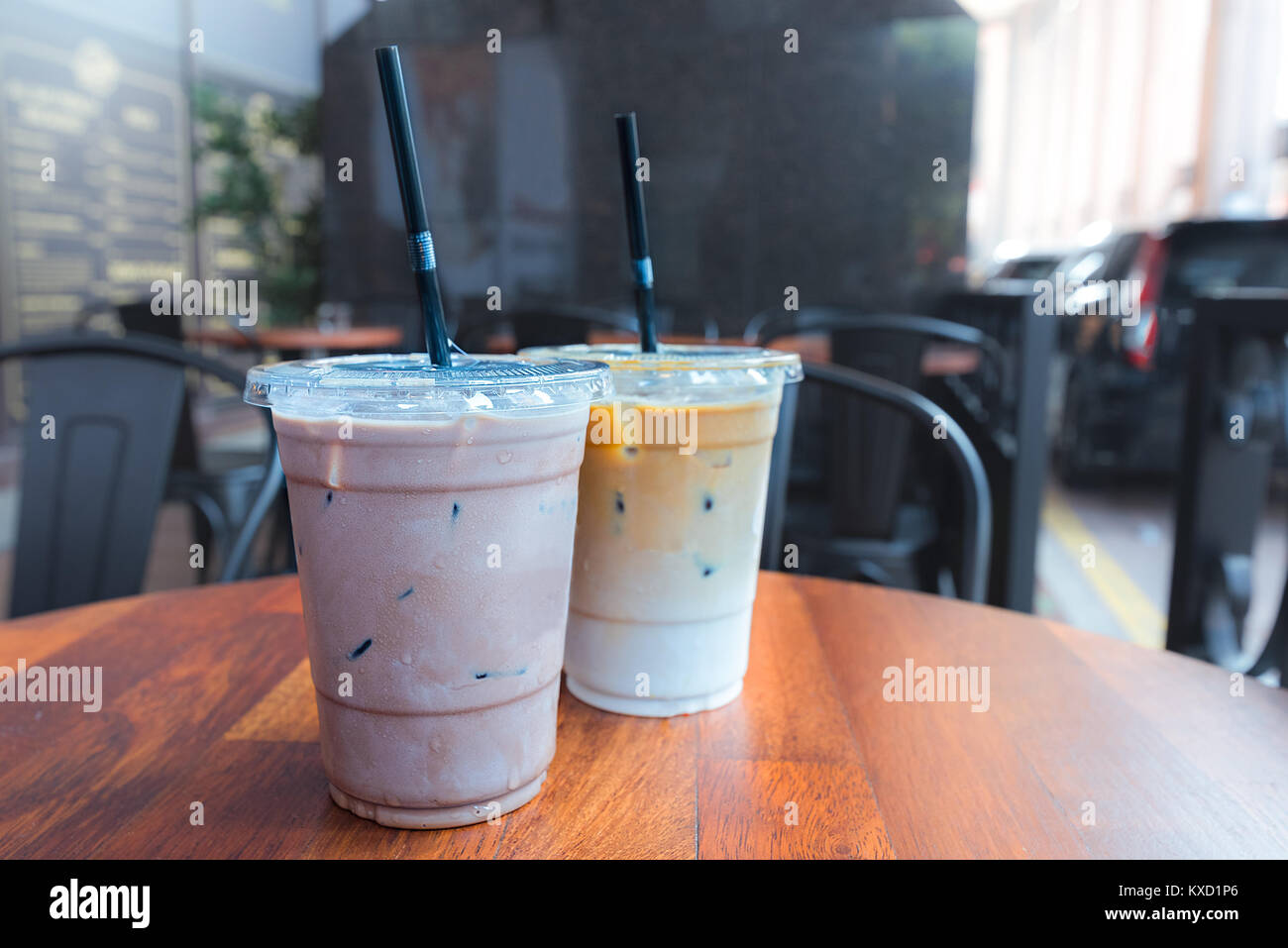 iced latte with straw in plastic cup on wood table in coffee shop