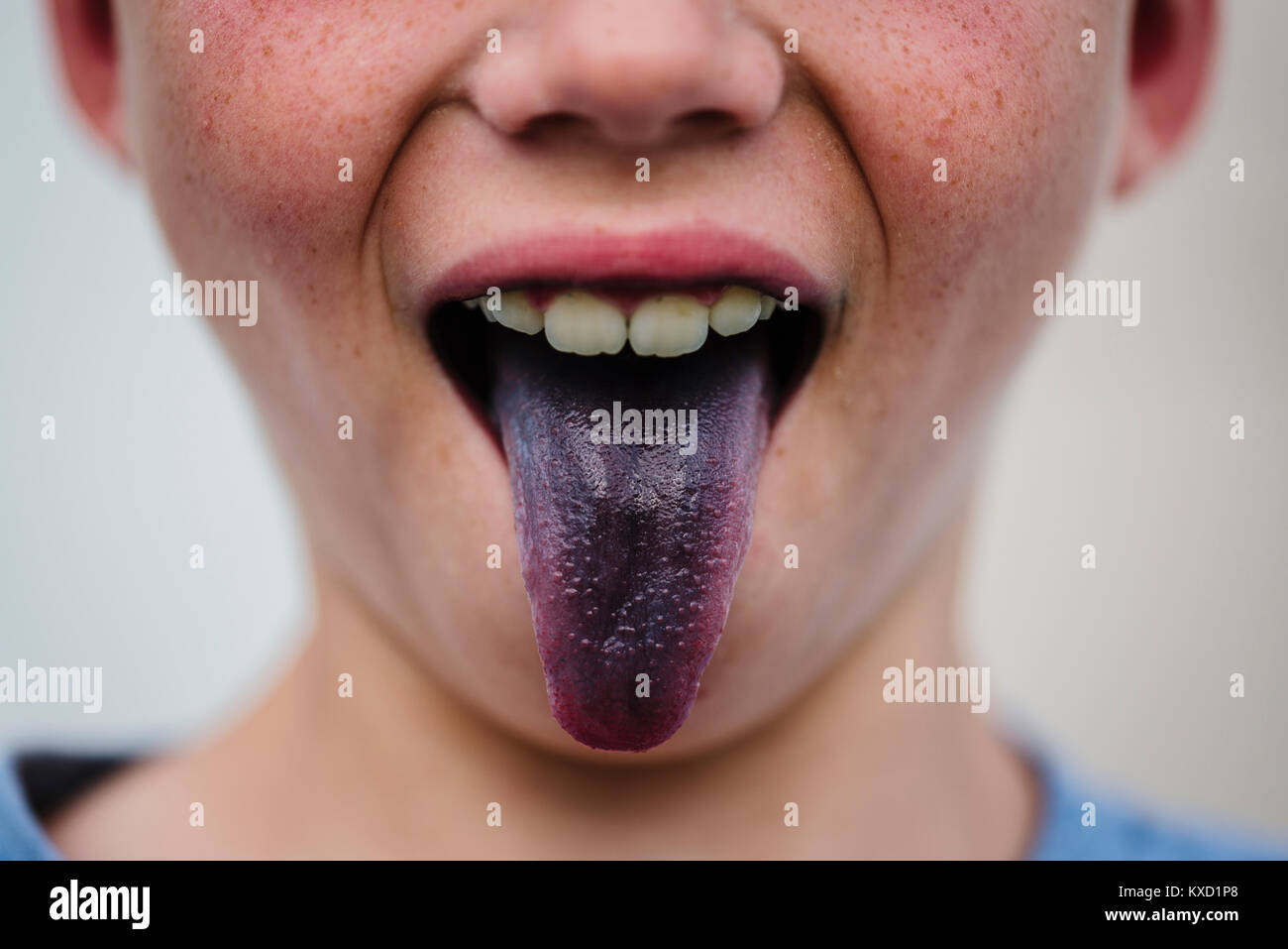 Midsection of boy sticking out purple tongue Stock Photo