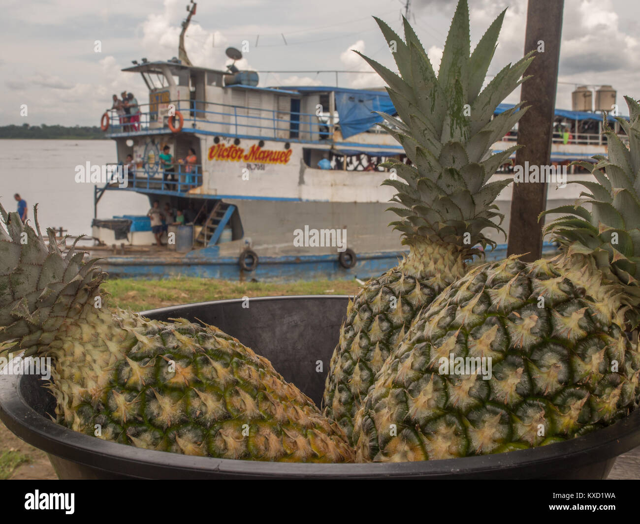 Amazon River, Peru - December 11, 2017: Pineapple in a bowl on the background of a cargo boat on the Amazon river Stock Photo