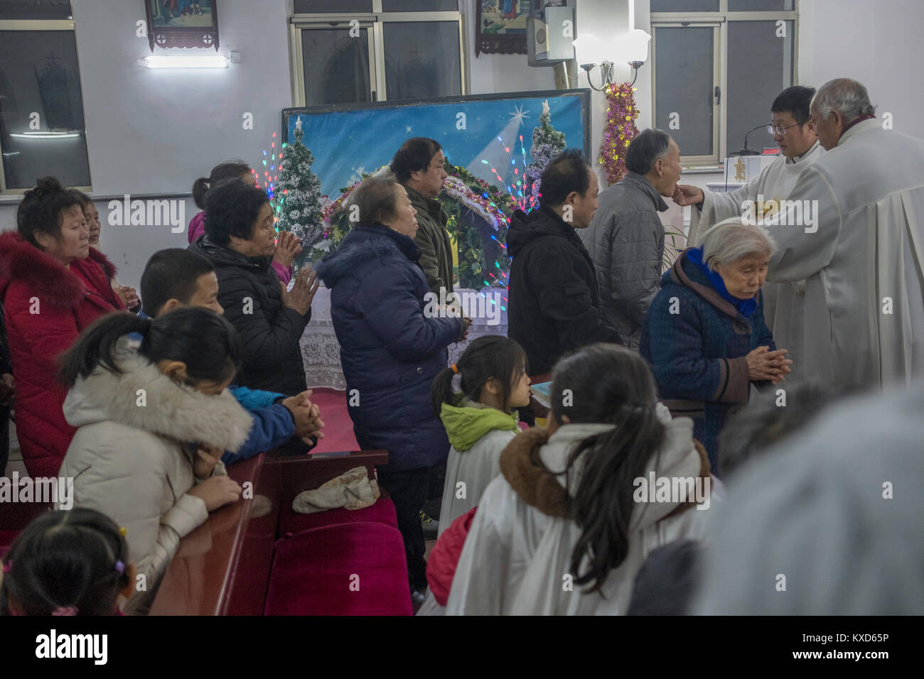 The Reverend Pang Ruowang giving communion to believers during Christmas Eve Mass at Sacred Heart of Jesus Church in Housangyu village, 70 kilometers west of Beijing center, one of the earliest churches in China. 24-Dec-2017 Stock Photo