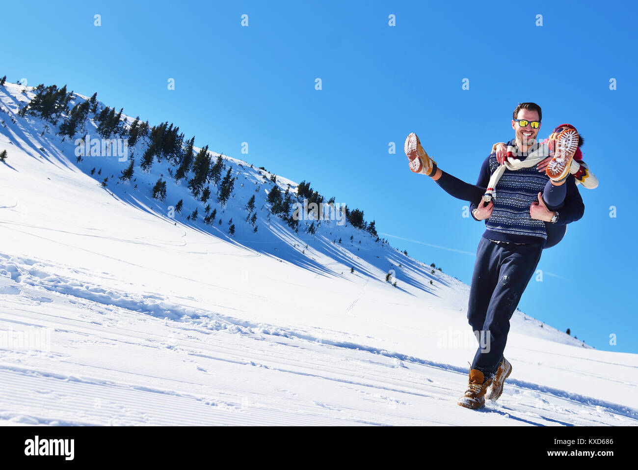 Young couple having fun on snow. Happy man at the mountain giving ...