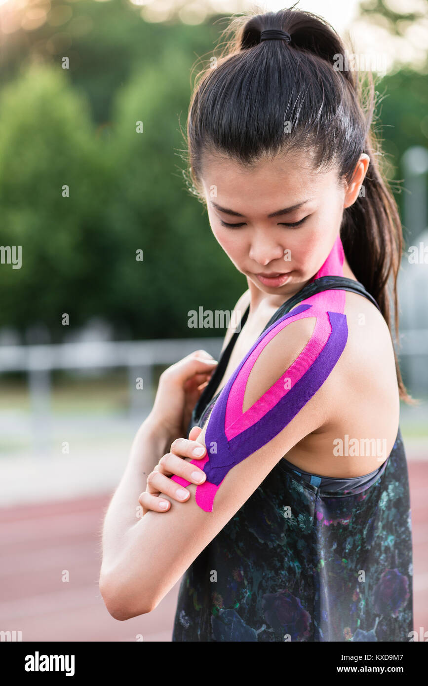 Woman taping with therapeutic tape on cinder track of sports sta Stock Photo