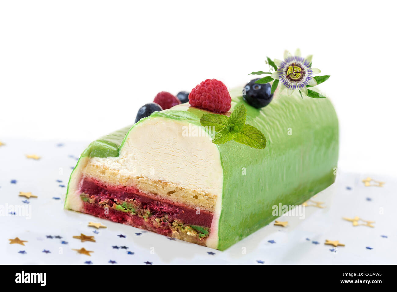 Pistachio Raspberry Yule Log decorated with fresh raspberries, blueberry, and pasion flower on white background. Stock Photo