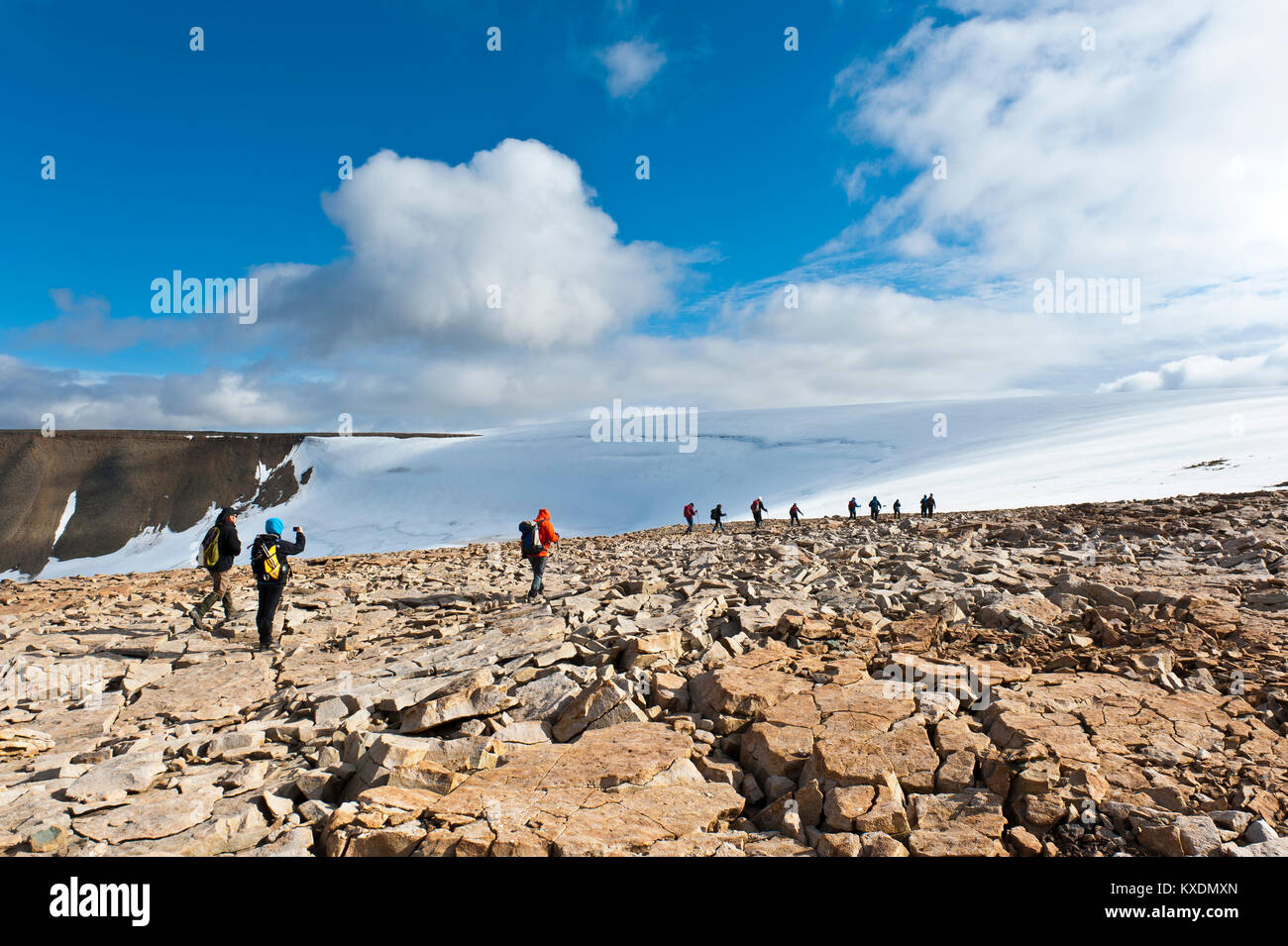 Hiking group in rocky terrain in front of Foxfonna glacier, near Longyearbyen, Spitsbergen, Svalbard, Norway Stock Photo