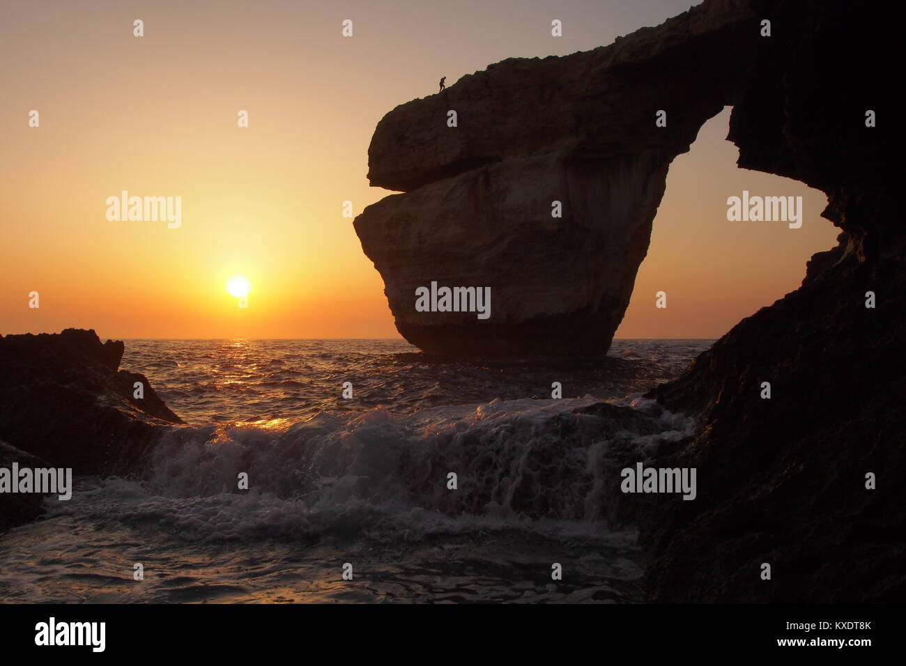 Tourist walking on the 'Azure window' natural arch at sunset, Gozo, Malta Stock Photo