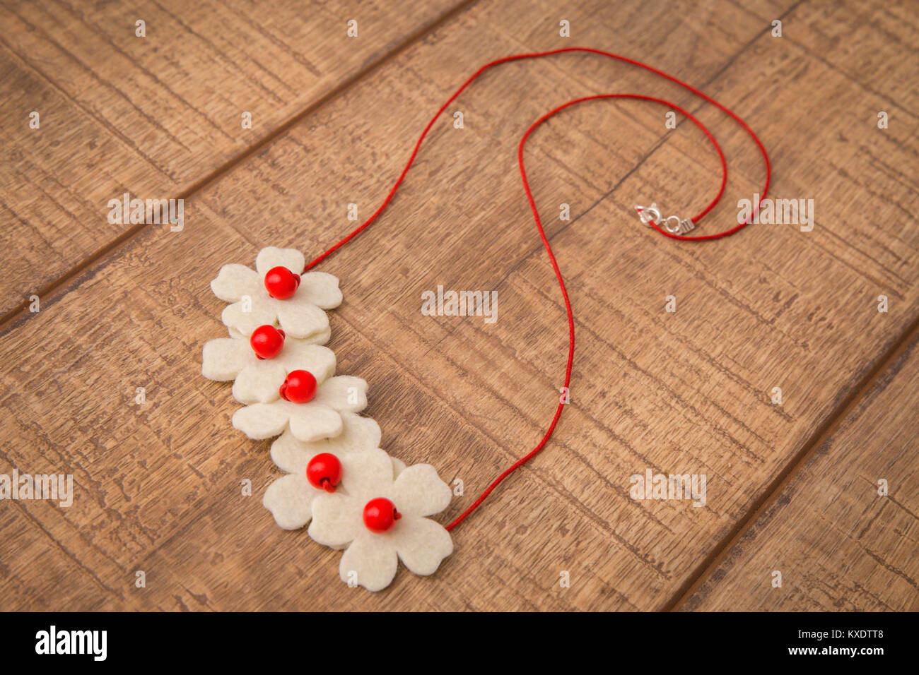 Colorful wood and wool felt flower shaped beads necklace hand painted with red and white color beads on a wood table background Stock Photo