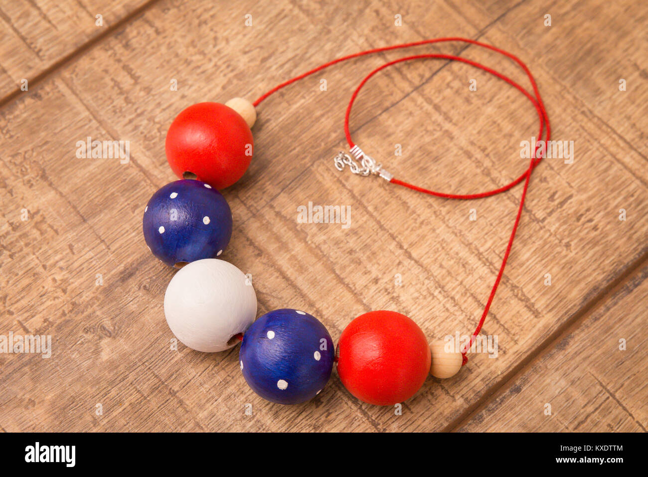 Colorful round wood beads necklace hand painted with blue, red, white and natural color beads on a wood table background Stock Photo