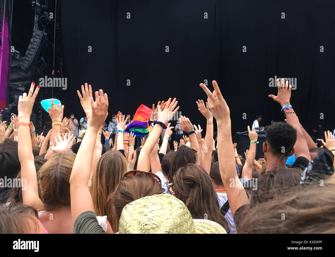 Audience with hands raised at a music festival, empty stage with copy space in the background Stock Photo