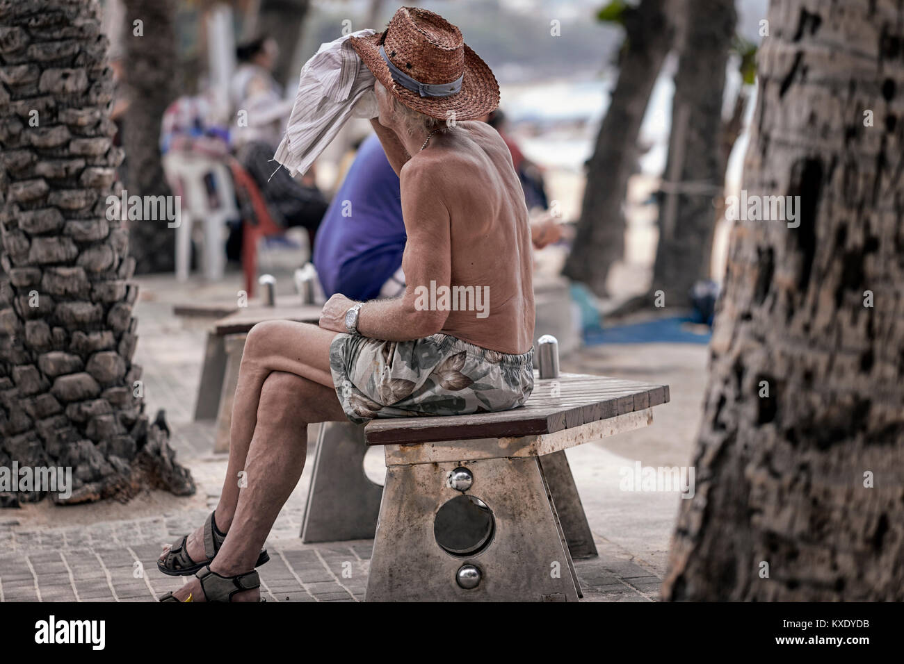 Man discreetly drinking alcohol outdoors using a towel to disguise his action. Stock Photo