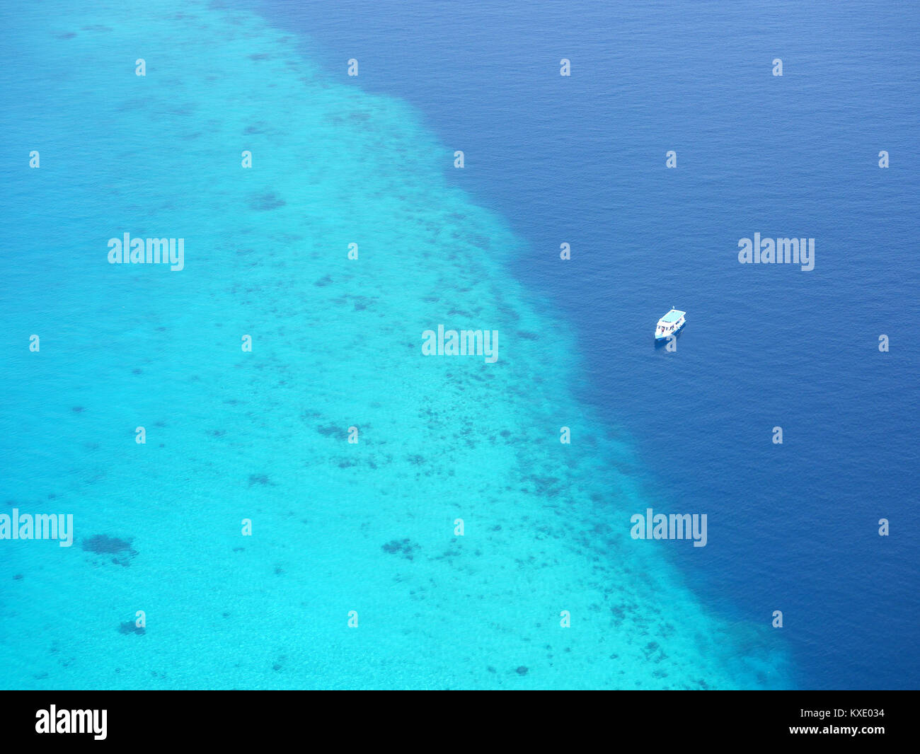 Aerial view of tourist ferry boat floating near coral reef of atoll in Maldives, famous tropical Indian Ocean destination in Asia. Stock Photo