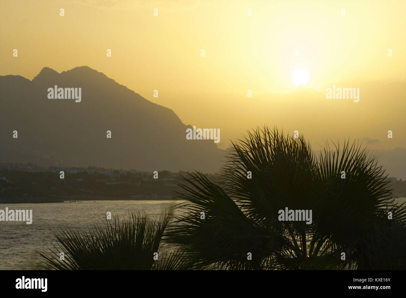 Sunset with the mountains and sea behind palm trees in Kyrenia, Cyprus Stock Photo