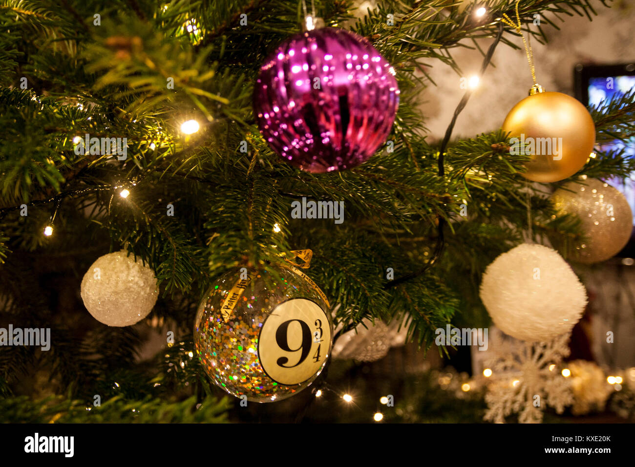 Closeup of purple gold, white and silver Christmas tree bauble decorations, baubles, harry potter decoration, hanging on a real tree with lights on. Stock Photo