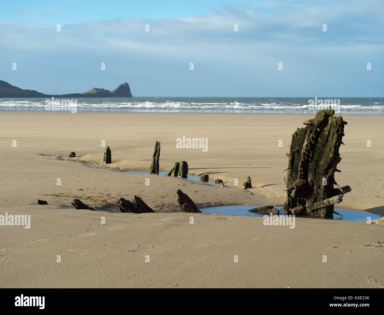 Remains of the wreck of the Helvetia at Rhossili Bay, Gower with Worm's Head in the background Stock Photo