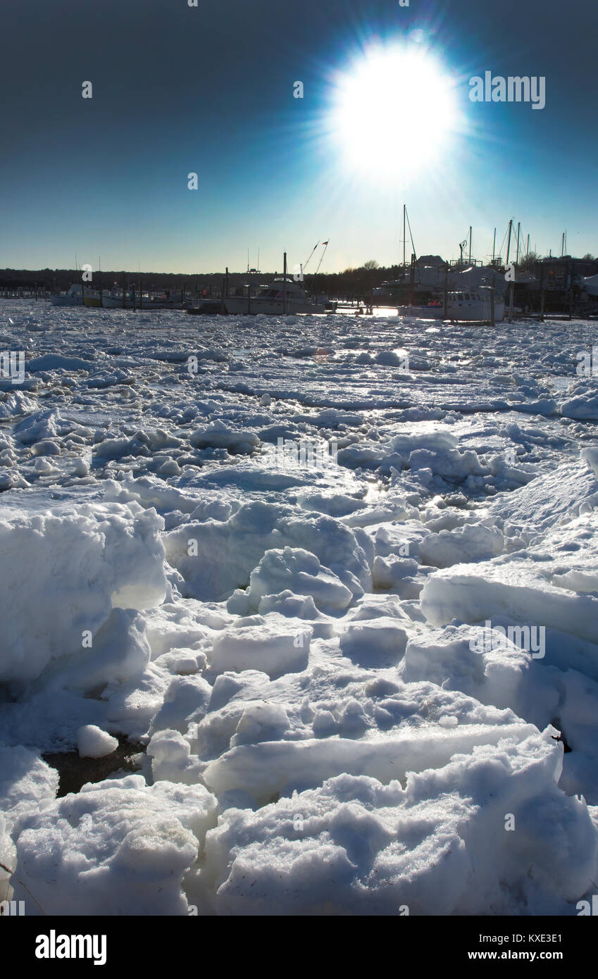 The sun over a frozen Sesuit Harbor in Dennis, Massachusetts on Cape Cod, USA Stock Photo