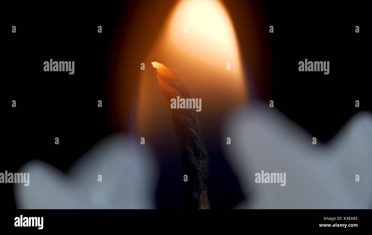 White long candle on black background. Single candle flame light. Long