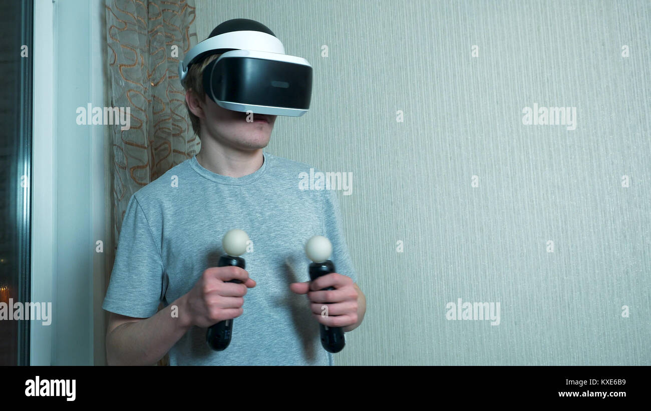Young man playing with virtual reality glasses and video game ...