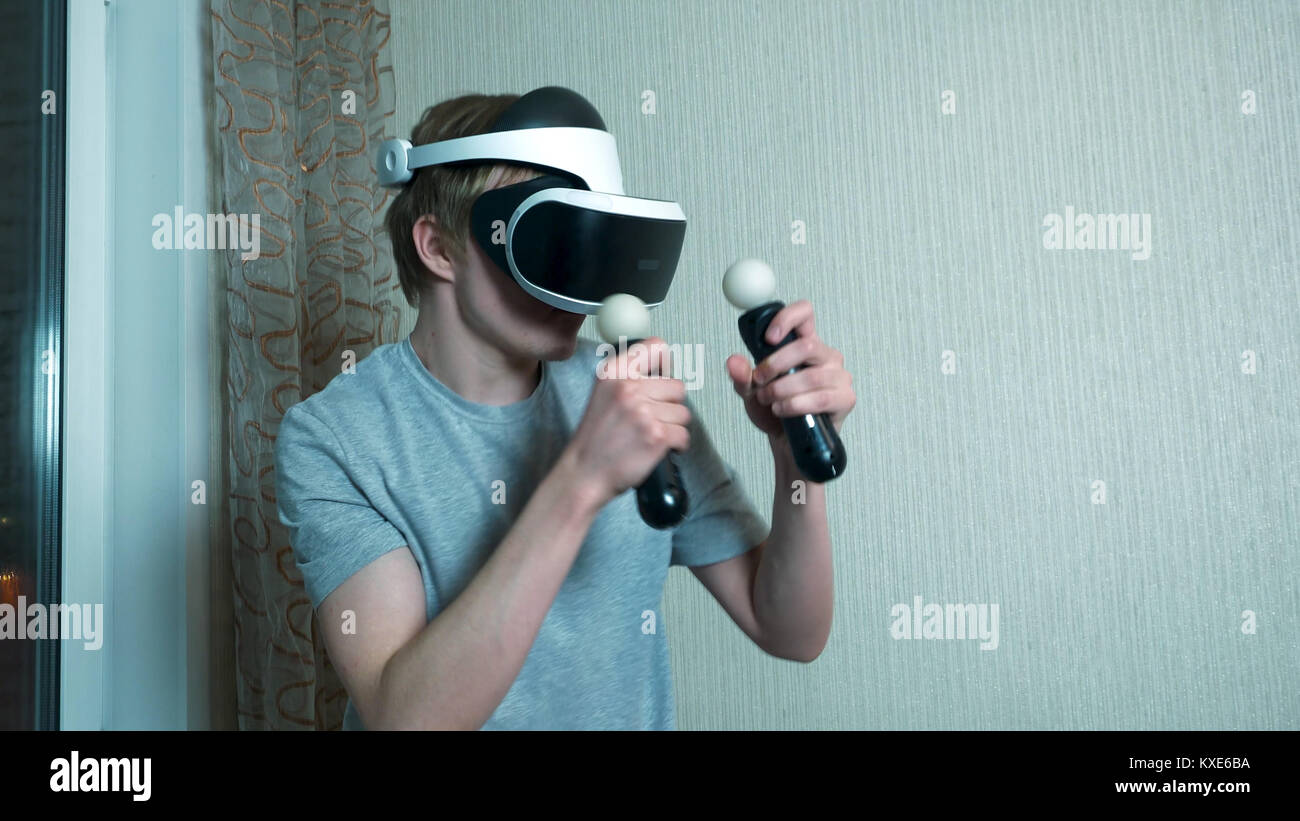 Young man playing with virtual reality glasses and video game ...