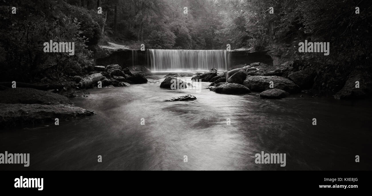 Nude woman laying among rocks at waterfall Stock Photo - Alamy