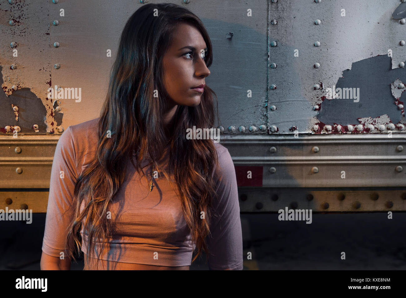 Young woman standing and hiding around semi trailers Stock Photo