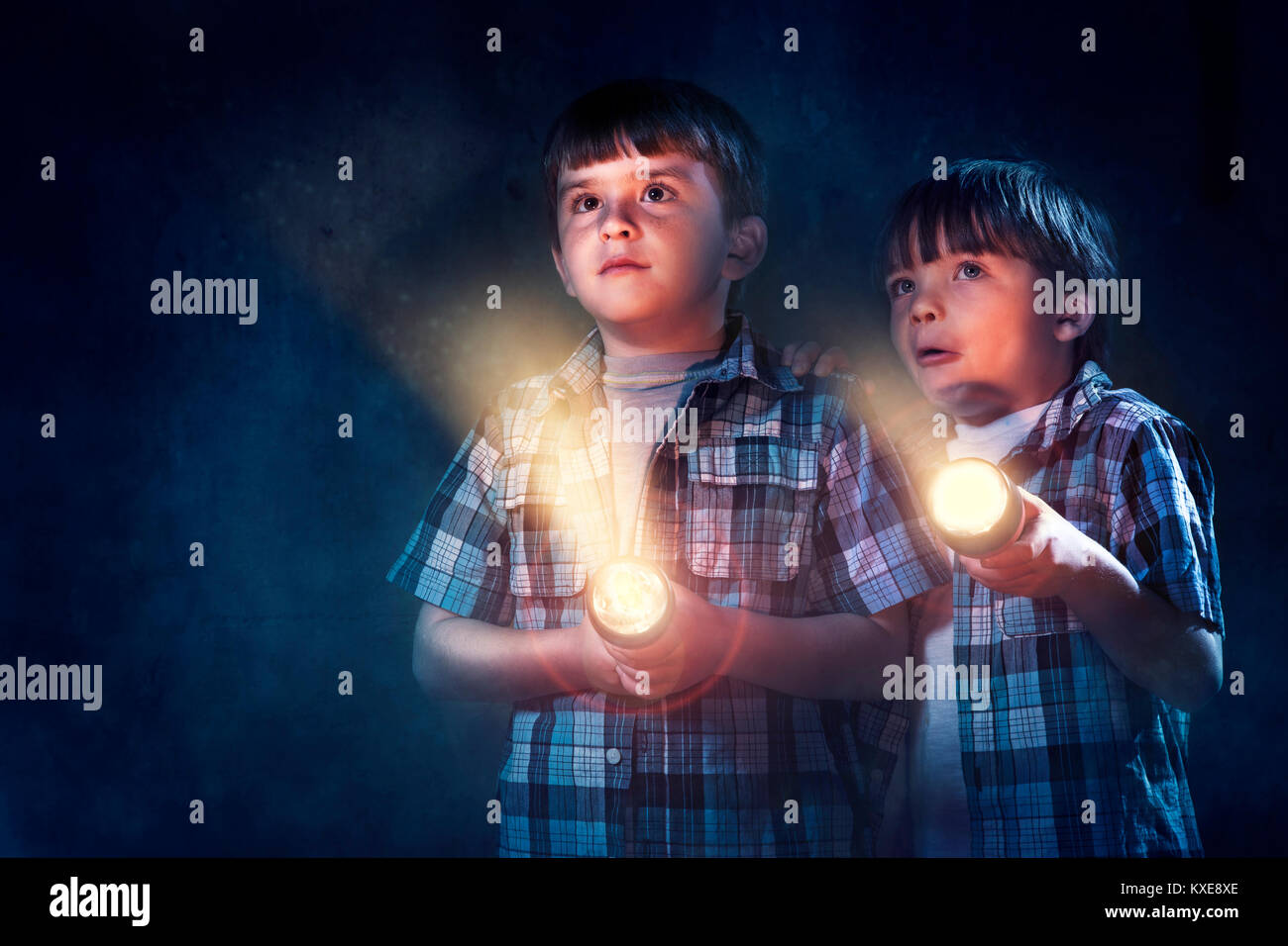 Young boys scared in dark with flashlight Stock Photo