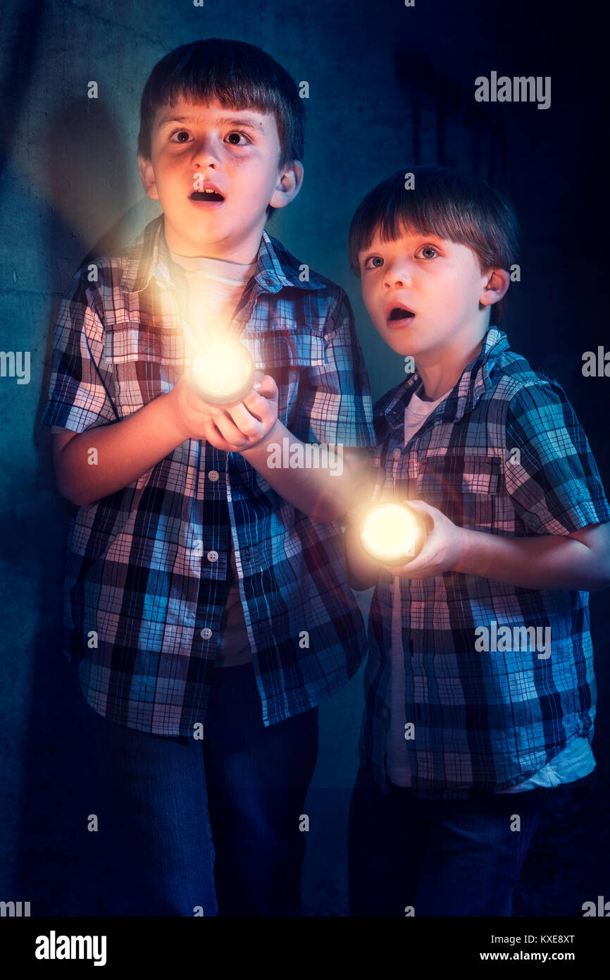 Young boys scared in dark with flashlight Stock Photo