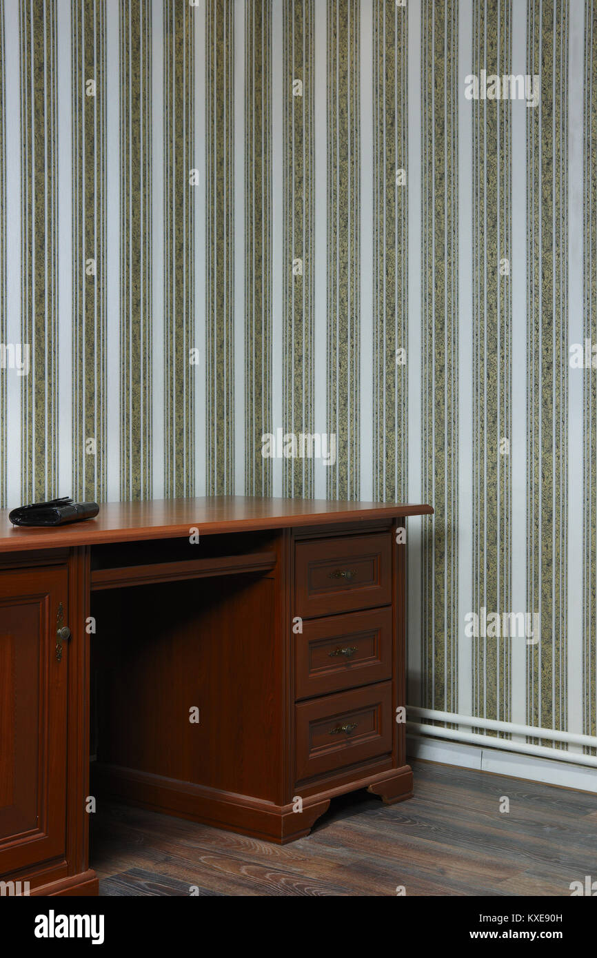 Old wooden table in the corner of the room with striped wallpaper Stock Photo