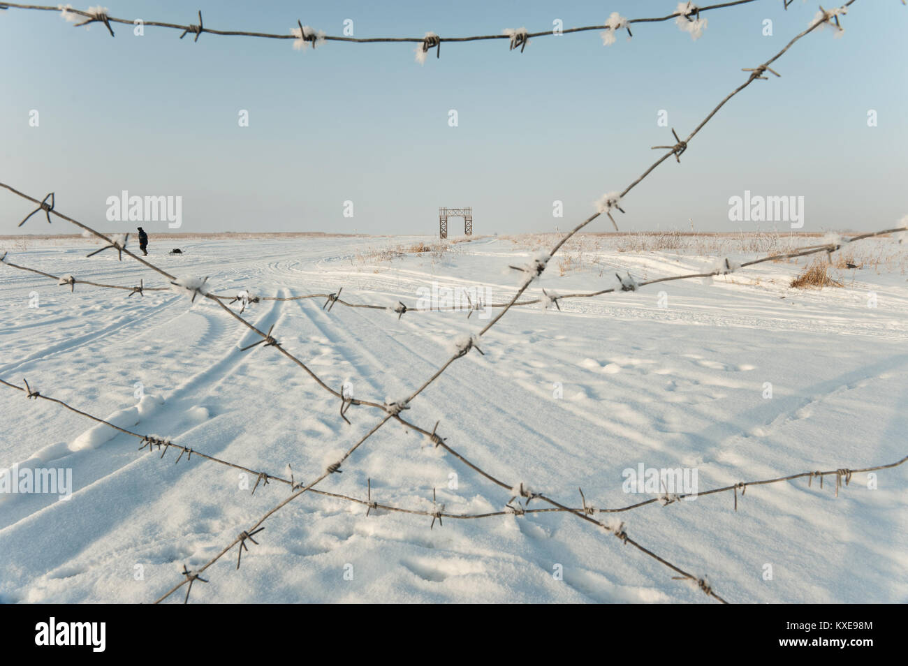 Barbed wire on a background of snow-covered landscape in sunny winter ...