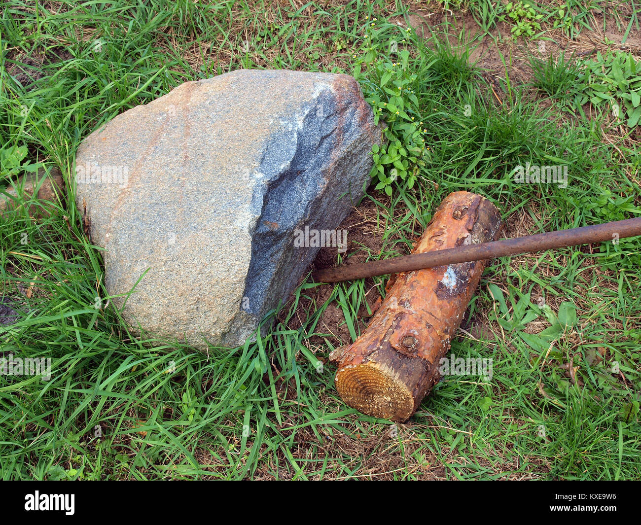 Lifting up heavy stone using iron lever supported on wooden log Stock