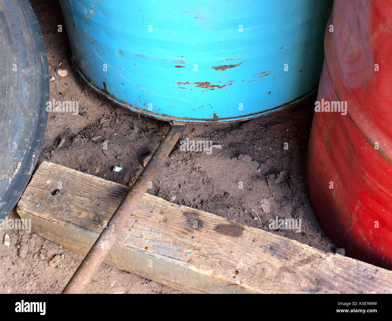 Lifting up heavy metal barrel using iron lever supported on wooden log Stock Photo